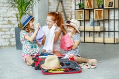 Τρία μικρά κορίτσια συσκεύασαν τα ενδύματά τους σε μια βαλίτσα Έννοια, στοκ εικόνες Τρία μικρά κορίτσια συσκεύασαν τα ενδύματά τους σε μια βαλίτσα Έννοια, στοκ εικόνες