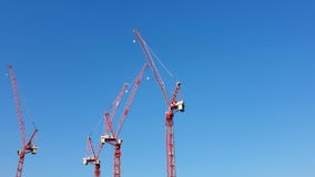 Τρεις γερανοί κατασκευής του κόκκινου χρώματος που στέκονται πλησίον ενάντια στον μπλε ασυννέφιαστο ουρανό Η άποψη από το σκάφος φιλμ μικρού μήκους Τρεις γερανοί κατασκευής του κόκκινου χρώματος που στέκονται πλησίον ενάντια στον μπλε ασυννέφιαστο ουρανό Η άποψη από το σκάφος φιλμ μικρού μήκους