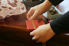 Τύλιγμα του κόκκινου δώρου με την κορδέλλα στον ξύλινο πίνακα στοκ εικόνα με δικαίωμα ελεύθερης χρήσης Τύλιγμα του κόκκινου δώρου με την κορδέλλα στον ξύλινο πίνακα στοκ εικόνα με δικαίωμα ελεύθερης χρήσης