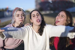 Υπαίθριο πορτρέτο τριών κοριτσιών διασκέδασης φίλων που παίρνουν τις φωτογραφίες με ένα smartphone στο φωτεινό ηλιοβασίλεμα στοκ φωτογραφία με δικαίωμα ελεύθερης χρήσης Υπαίθριο πορτρέτο τριών κοριτσιών διασκέδασης φίλων που παίρνουν τις φωτογραφίες με ένα smartphone στο φωτεινό ηλιοβασίλεμα στοκ φωτογραφία με δικαίωμα ελεύθερης χρήσης