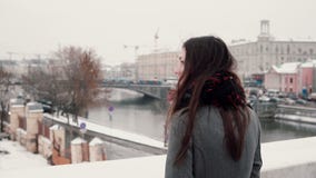 υποστηρίξτε την όψη Η ελκυστική νέα στάση κοριτσιών brunette στη γέφυρα και εξετάζει τη χιονισμένη χειμερινή πόλη στοκ φωτογραφία υποστηρίξτε την όψη Η ελκυστική νέα στάση κοριτσιών brunette στη γέφυρα και εξετάζει τη χιονισμένη χειμερινή πόλη στοκ φωτογραφία