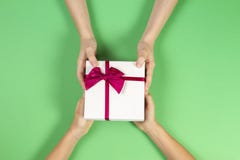 Υπόβαθρο συγχαρητηρίων Τοπ άποψη δύο χεριών προσώπων που δίνουν και που λαμβάνουν ένα παρόν κιβώτιο δώρων με την κορδέλλα σε πράσ στοκ φωτογραφίες Υπόβαθρο συγχαρητηρίων Τοπ άποψη δύο χεριών προσώπων που δίνουν και που λαμβάνουν ένα παρόν κιβώτιο δώρων με την κορδέλλα σε πράσ στοκ φωτογραφίες