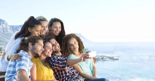 Φίλοι που παίρνουν τη φωτογραφία ομάδας ενάντια στη μουτζουρωμένη ακτή στοκ φωτογραφία με δικαίωμα ελεύθερης χρήσης Φίλοι που παίρνουν τη φωτογραφία ομάδας ενάντια στη μουτζουρωμένη ακτή στοκ φωτογραφία με δικαίωμα ελεύθερης χρήσης