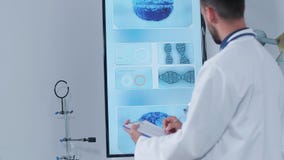 Φορητός πυροβολισμός του γιατρού στο σύγχρονο ερευνητικό κέντρο του που παίρνει τις σημειώσεις για μια περιοχή αποκομμάτων απόθεμα βίντεο Φορητός πυροβολισμός του γιατρού στο σύγχρονο ερευνητικό κέντρο του που παίρνει τις σημειώσεις για μια περιοχή αποκομμάτων απόθεμα βίντεο