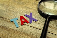 Φορολογική έννοια πιό magnifier και το ζωηρόχρωμο ξύλινο αλφάβητο στο ξύλινο υπόβαθρο στοκ εικόνες Φορολογική έννοια πιό magnifier και το ζωηρόχρωμο ξύλινο αλφάβητο στο ξύλινο υπόβαθρο στοκ εικόνες