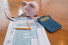 Φορολογική μορφή IRS με την τράπεζα Piggy και σπασμένο το υπολογιστής μολύβι στοκ φωτογραφία με δικαίωμα ελεύθερης χρήσης Φορολογική μορφή IRS με την τράπεζα Piggy και σπασμένο το υπολογιστής μολύβι στοκ φωτογραφία με δικαίωμα ελεύθερης χρήσης