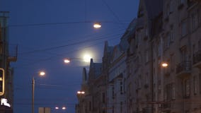 Φωτεινή πανσέληνος ορατή στις οδούς πόλεων που χρησιμοποιούν τον τηλε φακό φωτογραφιών με τα φω'τα πόλεων στο πρώτο πλάνο και τη φιλμ μικρού μήκους Φωτεινή πανσέληνος ορατή στις οδούς πόλεων που χρησιμοποιούν τον τηλε φακό φωτογραφιών με τα φω'τα πόλεων στο πρώτο πλάνο και τη φιλμ μικρού μήκους