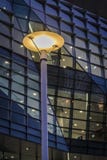 Φωτισμένος λαμπτήρας οδών ενάντια στο κτίριο γραφείων τη νύχτα στοκ εικόνα Φωτισμένος λαμπτήρας οδών ενάντια στο κτίριο γραφείων τη νύχτα στοκ εικόνα