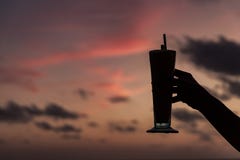 Χέρι γυναίκας που κρατά ένα κοκτέιλ ενάντια στο ηλιοβασίλεμα Ευτυχής ώρα στοκ φωτογραφίες Χέρι γυναίκας που κρατά ένα κοκτέιλ ενάντια στο ηλιοβασίλεμα Ευτυχής ώρα στοκ φωτογραφίες