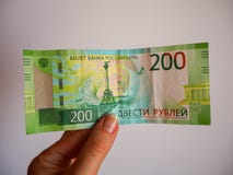 Χέρι γυναίκας που κρατά ένα νέο ρωσικό τραπεζογραμμάτιο διακόσιων ρουβλιών στοκ εικόνα με δικαίωμα ελεύθερης χρήσης Χέρι γυναίκας που κρατά ένα νέο ρωσικό τραπεζογραμμάτιο διακόσιων ρουβλιών στοκ εικόνα με δικαίωμα ελεύθερης χρήσης