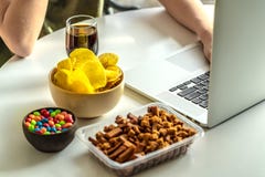 Χέρια γυναικών που δακτυλογραφούν στο lap-top και τα ανθυγειινά τρόφιμα στοκ φωτογραφία με δικαίωμα ελεύθερης χρήσης Χέρια γυναικών που δακτυλογραφούν στο lap-top και τα ανθυγειινά τρόφιμα στοκ φωτογραφία με δικαίωμα ελεύθερης χρήσης