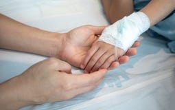 Χέρια μητέρων που κρατούν το υπομονετικό χέρι μωρών της με το αλατούχο intraveno στοκ εικόνες με δικαίωμα ελεύθερης χρήσης Χέρια μητέρων που κρατούν το υπομονετικό χέρι μωρών της με το αλατούχο intraveno στοκ εικόνες με δικαίωμα ελεύθερης χρήσης