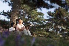 Χαλάρωση παππούδων και εγγονών κάτω από ένα δέντρο και ανάγνωση των βιβλίων σε ένα πάρκο στην άνοιξη, Πεκίνο στοκ φωτογραφίες με δικαίωμα ελεύθερης χρήσης Χαλάρωση παππούδων και εγγονών κάτω από ένα δέντρο και ανάγνωση των βιβλίων σε ένα πάρκο στην άνοιξη, Πεκίνο στοκ φωτογραφίες με δικαίωμα ελεύθερης χρήσης