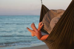 Χαλάρωση γυναικών στην αιώρα με το καπέλο που κάνει ηλιοθεραπεία στις διακοπές Στα πλαίσια της θάλασσας στον ήλιο ρύθμισης στοκ εικόνες Χαλάρωση γυναικών στην αιώρα με το καπέλο που κάνει ηλιοθεραπεία στις διακοπές Στα πλαίσια της θάλασσας στον ήλιο ρύθμισης στοκ εικόνες