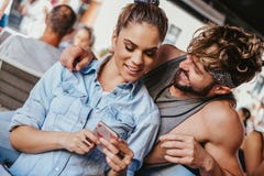 Χαμογελώντας φίλη που παρουσιάζει κινητό τηλέφωνο στο φίλο της στοκ εικόνες με δικαίωμα ελεύθερης χρήσης Χαμογελώντας φίλη που παρουσιάζει κινητό τηλέφωνο στο φίλο της στοκ εικόνες με δικαίωμα ελεύθερης χρήσης