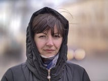 Χαριτωμένη νέα γυναίκα brunette σε μια κουκούλα σε μια οδό πόλεων που εξετάζει τη κάμερα στοκ εικόνα Χαριτωμένη νέα γυναίκα brunette σε μια κουκούλα σε μια οδό πόλεων που εξετάζει τη κάμερα στοκ εικόνα