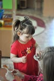 Χαριτωμένο μικρό κορίτσι που τρώει τις καραμέλες στον παιδικό σταθμό, σχολείο στοκ εικόνες Χαριτωμένο μικρό κορίτσι που τρώει τις καραμέλες στον παιδικό σταθμό, σχολείο στοκ εικόνες