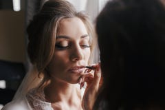 Χείλια ζωγραφικής καλλιτεχνών Makeup με το nude κραγιόν στο πρόσωπο γ της νύφης στοκ φωτογραφία με δικαίωμα ελεύθερης χρήσης Χείλια ζωγραφικής καλλιτεχνών Makeup με το nude κραγιόν στο πρόσωπο γ της νύφης στοκ φωτογραφία με δικαίωμα ελεύθερης χρήσης