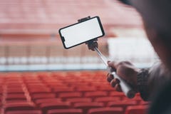 Χλεύη επάνω σε Smartphone με ένα ραβδί selfie στα χέρια ενός ατόμου στο υπόβαθρο των στάσεων Ο τύπος παίρνει ένα selfie στοκ εικόνα Χλεύη επάνω σε Smartphone με ένα ραβδί selfie στα χέρια ενός ατόμου στο υπόβαθρο των στάσεων Ο τύπος παίρνει ένα selfie στοκ εικόνα
