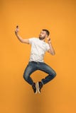 Χρόνος να πάρει selfie Πλήρες μήκος του όμορφου νεαρού άνδρα που παίρνει selfie πηδώντας στοκ εικόνες με δικαίωμα ελεύθερης χρήσης Χρόνος να πάρει selfie Πλήρες μήκος του όμορφου νεαρού άνδρα που παίρνει selfie πηδώντας στοκ εικόνες με δικαίωμα ελεύθερης χρήσης
