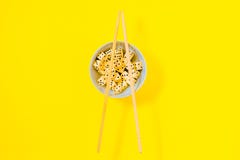 Χωρίστε σε τετράγωνα στο άσπρο κύπελλο με chopsticks στο κίτρινο υπόβαθρο στοκ εικόνα Χωρίστε σε τετράγωνα στο άσπρο κύπελλο με chopsticks στο κίτρινο υπόβαθρο στοκ εικόνα