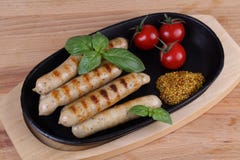 Ψημένα στη σχάρα λουκάνικα με τις ντομάτες, τη μουστάρδα και το βασιλικό σε ένα ξύλινο υπόβαθρο Στοκ Εικόνα Ψημένα στη σχάρα λουκάνικα με τις ντομάτες, τη μουστάρδα και το βασιλικό σε ένα ξύλινο υπόβαθρο Στοκ Εικόνα