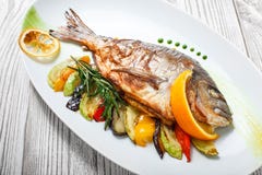 Ψημένα στη σχάρα ψάρια dorado με τα ψημένα λαχανικά και δεντρολίβανο στο πιάτο στο ξύλινο υπόβαθρο κοντά επάνω στοκ φωτογραφία με δικαίωμα ελεύθερης χρήσης Ψημένα στη σχάρα ψάρια dorado με τα ψημένα λαχανικά και δεντρολίβανο στο πιάτο στο ξύλινο υπόβαθρο κοντά επάνω στοκ φωτογραφία με δικαίωμα ελεύθερης χρήσης