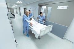 Ωθώντας κρεβάτι φορείων έκτακτης ανάγκης ιατρικής ομάδας στο διάδρομο στοκ εικόνες Ωθώντας κρεβάτι φορείων έκτακτης ανάγκης ιατρικής ομάδας στο διάδρομο στοκ εικόνες