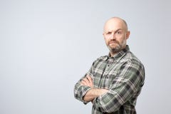Ωριμάστε το φαλακρό άτομο στο ελεγμένο πουκάμισο που στέκεται με τα όπλα που διασχίζονται και το σοβαρό πρόσωπο στη κάμερα, που φ στοκ εικόνες Ωριμάστε το φαλακρό άτομο στο ελεγμένο πουκάμισο που στέκεται με τα όπλα που διασχίζονται και το σοβαρό πρόσωπο στη κάμερα, που φ στοκ εικόνες