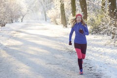 Όμορφη γυναίκα Jogging το χειμώνα με τα ακουστικά στοκ εικόνα Όμορφη γυναίκα Jogging το χειμώνα με τα ακουστικά στοκ εικόνα