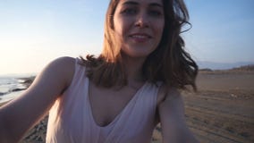 Όμορφη γυναίκα που παίρνει selfie χρησιμοποιώντας το τηλέφωνο στην παραλία στο ηλιοβασίλεμα που χαμογελά και που περιστρέφει απολ Όμορφη γυναίκα που παίρνει selfie χρησιμοποιώντας το τηλέφωνο στην παραλία στο ηλιοβασίλεμα που χαμογελά και που περιστρέφει απολ