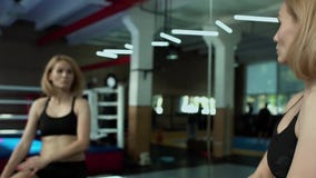 Όμορφη γυναίκα που φορά sportswear που τεντώνει το σώμα της μπροστά από τον καθρέφτη στη γυμναστική απόθεμα βίντεο Όμορφη γυναίκα που φορά sportswear που τεντώνει το σώμα της μπροστά από τον καθρέφτη στη γυμναστική απόθεμα βίντεο