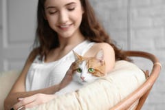 Όμορφη νέα γυναίκα με τη χαριτωμένη γάτα στην πολυθρόνα στοκ εικόνα Όμορφη νέα γυναίκα με τη χαριτωμένη γάτα στην πολυθρόνα στοκ εικόνα
