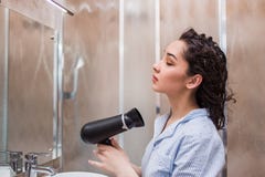Όμορφη νέα ξεραίνοντας τρίχα γυναικών μετά από το ντους στο ελαφρύ λουτρό στο σπίτι στοκ εικόνες Όμορφη νέα ξεραίνοντας τρίχα γυναικών μετά από το ντους στο ελαφρύ λουτρό στο σπίτι στοκ εικόνες
