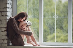Όμορφη νέα συνεδρίαση γυναικών μόνο κοντά στο παράθυρο με τις πτώσεις βροχής Προκλητικό και λυπημένο κορίτσι Έννοια της μοναξιάς Όμορφη νέα συνεδρίαση γυναικών μόνο κοντά στο παράθυρο με τις πτώσεις βροχής Προκλητικό και λυπημένο κορίτσι Έννοια της μοναξιάς