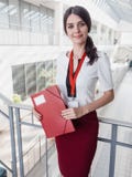 Όμορφη χαμογελώντας επιχειρηματίας που στέκεται στο άσπρο κλίμα γραφείων Πορτρέτο της επιχειρησιακής γυναίκας με έναν φάκελλο στα Στοκ φωτογραφία με δικαίωμα ελεύθερης χρήσης Όμορφη χαμογελώντας επιχειρηματίας που στέκεται στο άσπρο κλίμα γραφείων Πορτρέτο της επιχειρησιακής γυναίκας με έναν φάκελλο στα Στοκ φωτογραφία με δικαίωμα ελεύθερης χρήσης