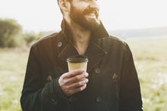 Όμορφο γενειοφόρο άτομο με το φλιτζάνι του καφέ εγγράφου Στοκ φωτογραφίες με δικαίωμα ελεύθερης χρήσης Όμορφο γενειοφόρο άτομο με το φλιτζάνι του καφέ εγγράφου Στοκ φωτογραφίες με δικαίωμα ελεύθερης χρήσης