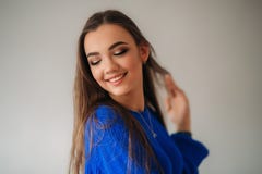 Όμορφο κορίτσι brunette με ένα καλό χαμόγελο σε μια μπλε τοποθέτηση μπλουζών για έναν φωτογράφο και την παρουσίαση makeup της στοκ εικόνες Όμορφο κορίτσι brunette με ένα καλό χαμόγελο σε μια μπλε τοποθέτηση μπλουζών για έναν φωτογράφο και την παρουσίαση makeup της στοκ εικόνες