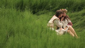 Όμορφο κορίτσι brunette στο παραδοσιακό ουκρανικό πουκάμισο με το στεφάνι λουλουδιών που αγκαλιάζει το φίλο στον τομέα απόθεμα βίντεο Όμορφο κορίτσι brunette στο παραδοσιακό ουκρανικό πουκάμισο με το στεφάνι λουλουδιών που αγκαλιάζει το φίλο στον τομέα απόθεμα βίντεο