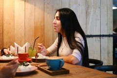 Όμορφο κορίτσι που μιλά, που ακούει, που τρώει και που χαμογελά στον πίνακα στο γ στοκ φωτογραφία Όμορφο κορίτσι που μιλά, που ακούει, που τρώει και που χαμογελά στον πίνακα στο γ στοκ φωτογραφία