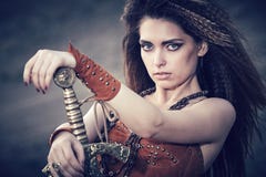 Όμορφο κορίτσι στα ενδύματα ενός Βίκινγκ ή του Αμαζονίου, με ένα swor στοκ εικόνα με δικαίωμα ελεύθερης χρήσης Όμορφο κορίτσι στα ενδύματα ενός Βίκινγκ ή του Αμαζονίου, με ένα swor στοκ εικόνα με δικαίωμα ελεύθερης χρήσης