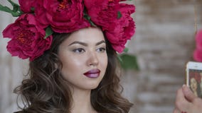 Όμορφο πρότυπο, με ένα στεφάνι των ερυθρών peonies στο κεφάλι του Το πρότυπο φωτογραφίζεται στο τηλέφωνο, ένα smartphone στοκ εικόνα με δικαίωμα ελεύθερης χρήσης Όμορφο πρότυπο, με ένα στεφάνι των ερυθρών peonies στο κεφάλι του Το πρότυπο φωτογραφίζεται στο τηλέφωνο, ένα smartphone στοκ εικόνα με δικαίωμα ελεύθερης χρήσης