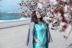 Όμορφο πρότυπο στο μπλε φόρεμα και γκρίζο παλτό από το ανθίζοντας δέντρο άνοιξη στοκ φωτογραφίες με δικαίωμα ελεύθερης χρήσης Όμορφο πρότυπο στο μπλε φόρεμα και γκρίζο παλτό από το ανθίζοντας δέντρο άνοιξη στοκ φωτογραφίες με δικαίωμα ελεύθερης χρήσης