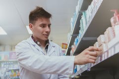 Όμορφος αρσενικός φαρμακοποιός που εργάζεται στο φαρμακείο του στοκ φωτογραφία με δικαίωμα ελεύθερης χρήσης Όμορφος αρσενικός φαρμακοποιός που εργάζεται στο φαρμακείο του στοκ φωτογραφία με δικαίωμα ελεύθερης χρήσης