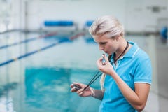 Όμορφος εκπαιδευτής που εξετάζει το χρονόμετρο με διακόπτη στοκ φωτογραφία με δικαίωμα ελεύθερης χρήσης Όμορφος εκπαιδευτής που εξετάζει το χρονόμετρο με διακόπτη στοκ φωτογραφία με δικαίωμα ελεύθερης χρήσης