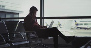 Όμορφος νεαρός άνδρας στον αερολιμένα που μιλά στο τηλέφωνό του στο ίδιο πράγμα έκλεισε το σημειωματάριό του και πηγαίνει να πάρε απόθεμα βίντεο Όμορφος νεαρός άνδρας στον αερολιμένα που μιλά στο τηλέφωνό του στο ίδιο πράγμα έκλεισε το σημειωματάριό του και πηγαίνει να πάρε απόθεμα βίντεο