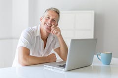 Ώριμο άτομο που χρησιμοποιεί το lap-top στο γραφείο στο σπίτι στοκ φωτογραφία με δικαίωμα ελεύθερης χρήσης Ώριμο άτομο που χρησιμοποιεί το lap-top στο γραφείο στο σπίτι στοκ φωτογραφία με δικαίωμα ελεύθερης χρήσης