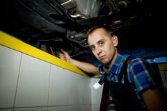 Автоматический механик работая под поднятым автомобилем Стоковые Фото Автоматический механик работая под поднятым автомобилем Стоковые Фото