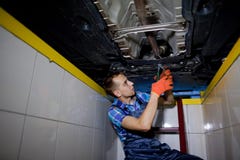 Автоматический механик работая под поднятым автомобилем Стоковая Фотография Автоматический механик работая под поднятым автомобилем Стоковая Фотография
