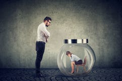 Авторитарный бизнесмен босса смотря стеклянный опарник с захваченной внутренностью женщины стоковая фотография rf Авторитарный бизнесмен босса смотря стеклянный опарник с захваченной внутренностью женщины стоковая фотография rf
